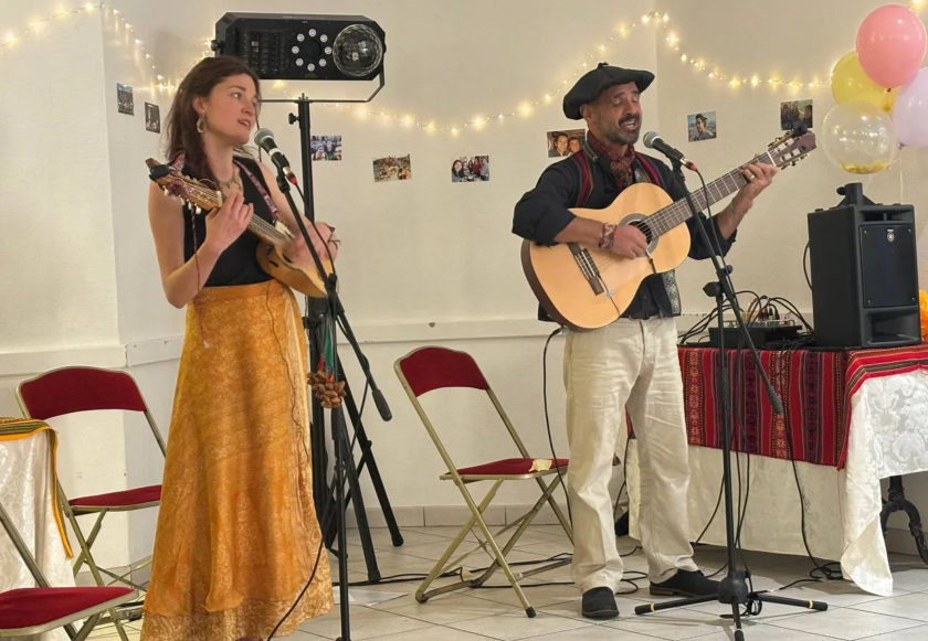 Duo de musiciens andins jouant dans une grande pièce décorée de guirlandes