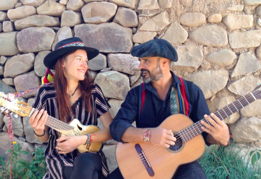 Deux musiciens assis devant un mur de pierres sèches